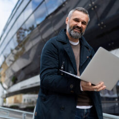 successful businessman with a laptop in his hands on the background of an office building.